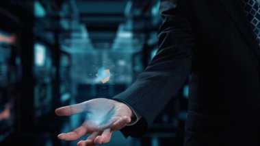 Bir işadamı, yenilik ve teknolojiyi temsil eden parlak bir modern çalışma alanında veri görselleştirme ve analizlerini gösteren parıldayan bir dijital arayüz tutuyor. Dörtgen