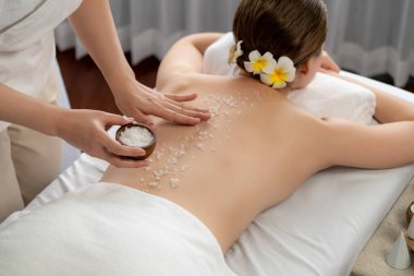 Lüks spa salonlarında sıcak mum ışığında cilt bakımı yaptıran kadın müşteri. Sağlık Spa vücut fırçasında tuz temizleme güzellik tedavisi. Sessiz.