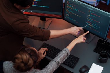 Akıllı web sitesi geliştirme kodlayıcı sistemi ile tartışan IT geliştiricilerinin üst görüşü modern ofisteki neon ışık odasında iki ekran bilgi teknolojisini çevrimiçi çalıştırıyor. İnfobahn.