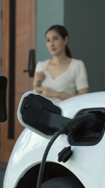 Bir kadın evinde elektrikli araç şarj aletinin fişini çekiyor. İlerici bir yaşam tarzında elektrikli araçların kullanımı, temiz ve sağlıklı bir çevreye katkıda bulunur..