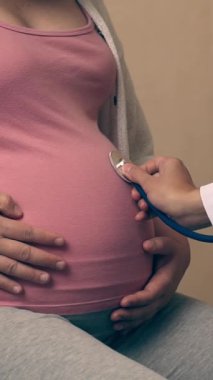 Mutlu hamile kadın, jinekolog doktoru hastanede ya da klinikte hamilelik danışmanlığı için ziyaret ediyor. Doktor, bebek ve anne sağlığı kontrolü için hamile karnı muayene ediyor. Jinekoloji konsepti.