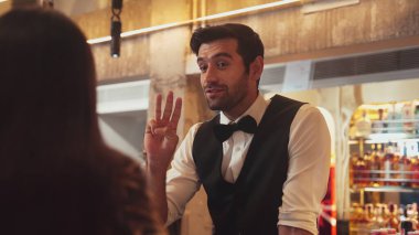 Akıllı barmenin VIP konuğuyla dostça sohbet etmesine odaklanıyorum. Cuma gecesi özel gece partisinde müşterilerin arka tarafındaki lüks tezgahta oturuyorlar. Vinosity.