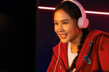 Portre sunucusu güzel Asyalı kız flamasının çevrimiçi oyun oynaması kulaklık takması pastel renkli konuşmalar izleyici medyası ile çevrimiçi. Esport yetenekli takım oyuncuları neon mavi odada. Taktik.