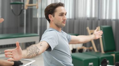 Pilates reformatör makinelerinde senkronize kol uzantıları yapan iki müşteri. Mutlu pilates partnerleri, esnekliği arttırmak ve dengeyi ve kontrolü sağlamak için reformcunun üzerine oturdular. Alışkanlık.