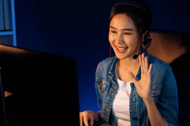 Sunucu kanalı Asyalı etkileyicisi canlı yayında konuşuyor. Sosyal medyada kulaklık takıyor, bilgisayar kaydı yapıyor, dinleyicileri selamlıyor ve Neon Modern Stüdyoları 'nda online olarak koçluk yapıyor. Taktik.