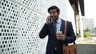 İş adamı telefona cevap verir ve iş yatırımları hakkında konuşur. İş planı, pazarlama stratejisi ya da çalışma hakkında konuşmak için akıllı telefonla konuşurken sokakta yürüyen mutlu bir yönetici. Sevinçli..