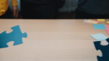 Ofisteki ortak bir toplantı sırasında renkli yapboz parçalarıyla birlikte çalışan çeşitli iş dünyasından profesyonellerin yakın çekimi. SACTR