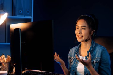 Sunucu kanalı Asyalı etkileyicisi canlı yayında konuşuyor. Sosyal medyada kulaklık takıyor, bilgisayar kaydı yapıyor, dinleyicileri selamlıyor ve Neon Modern Stüdyoları 'nda online olarak koçluk yapıyor. Taktik.