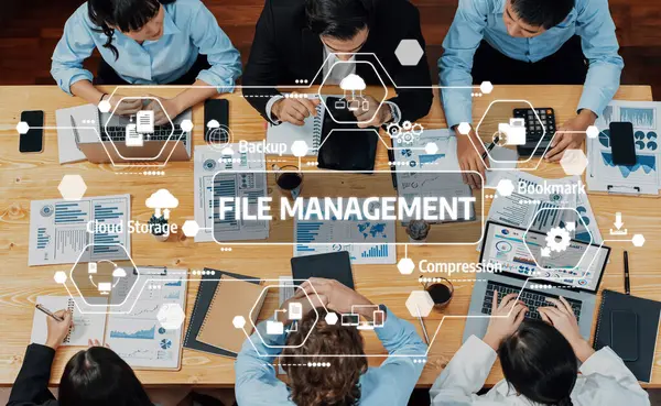 Bir iş ekibi, etkin karar verme işlemleri için teknoloji araçları, çizelgeler ve belgeler kullanarak, dosya yönetimi stratejileri üzerinde odaklanan bir ortak toplantıya katılıyor. Dostluk