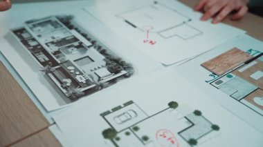 Odaklanmış bir tasarımcı, ev içi tasarımın yaratıcı sürecine girişir, ahşap bir masadaki planlar ve konseptler üzerine çizimler yapar, yenilikçi fikirler ve stratejiler sergiler. SACTR