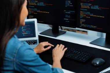 İnternet sitesi uygulamasının kodlama verileriyle birlikte online bilgi yazarak kot gömlek giyen genç Asyalı geliştirici. Güvenlik analizi ile çevrili iki ekran. Taktik.