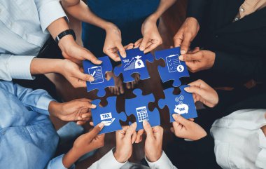Yapboz parçalarını birleştirmek için birlikte çalışan çeşitli bir grup el, ticari başarı için mali planlama ve vergi stratejisinde takım çalışmasını ve işbirliğini sembolize ediyor. Dostluk