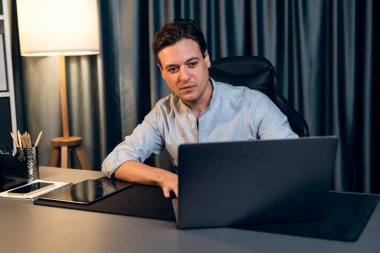 Akıllı iş adamı, gece vakti mavi perde arkasında iş hedefi olan finansal teknoloji veri raporlarını analiz etmek için veritabanı stoklarını araştırmak üzere dizüstü bilgisayarda uzaktan çalışıyor. Bireysel.