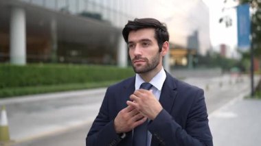 Profesyonel iş adamı yolda yürürken kravatı ayarlar. Yönetici şehre bakarken takım elbise giyiyor. Yatırımcı görüşmeye gitmeden önce kendini kontrol etmiş. Arka plan bulanık. Sevinçli..