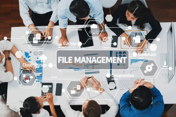 Çeşitli bir ekip, modern bir ofiste dosya yönetimi çözümleri üzerinde, etkin veri organizasyonu ve proje başarısı için teknolojiyi kullanarak işbirliği yapmaktadır. Dostluk