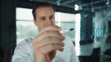 Akıllı iş adamı cam tahtanın önünde bir proje başlatmayı düşünüyor. Gülümseyen erkek proje yöneticisi yaratıcılık pazarlama stratejisini gösteren renkli yapışkan notlara bakıyor. Yönlendirici.