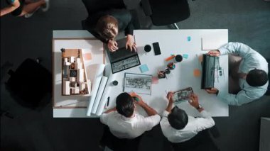 Ev modeli ve dizüstü bilgisayarla toplantı masasında otururken planda yazan akıllı mimar mühendisinin üst görüntüsü. Becerikli bir yönetici bina inşaatı konusunda çalışıyor. Hizalama.