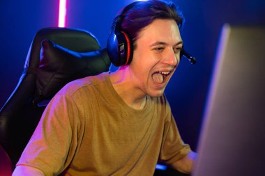 Kazanmak için çevrimiçi oyun oynayan akıllı flama makinesinin sunucu kanalı, neon ışıklı odada seçilen takım yarışması için izleyicilerle birlikte canlı yayında canlı yayında kulaklık takıyor. Bireysel.