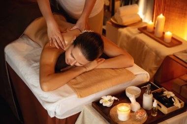 Beyaz kadın müşteri stres önleyici spa masajının keyfini çıkarıyor ve lüks otel ya da otelde sıcak mum ışığında güzellik teniyle eğleniyor. Sessiz.