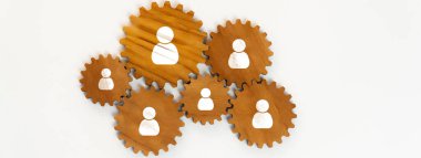 Ahşap dişliler ve insan simgeleriyle ağ oluşturma ve işbirliğinin yaratıcı bir temsili, profesyonel bir ortamda bağlantıları ve takım çalışmasını sembolize ediyor. Dostluk