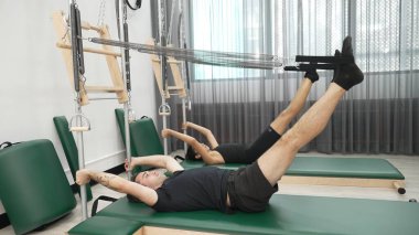 Bir grup müşteri, çekirdek dayanıklılığını ve bacak bağını geliştirmek için Cadillac reformatör makinesinde pilates egzersizleri yapıyor. Sağlıklı müşterilerin daha düşük poz verip kaldırma pozlarının üst görüntüsü. Sağlıklılık. Alışkanlık.