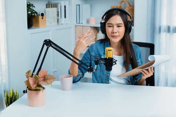 Ведущий азиатского канала, говорящий в потоковом онлайн-вещании в наушниках в социальных сетях в прямом эфире со сценарием, приветствуя слушателей в обучении жизни или маркетинге в современной студии. Стратагем.