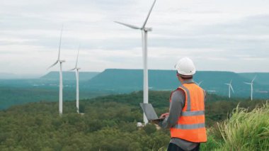 Kırsal kesimdeki bir tepenin tepesinde ya da dağda rüzgar çiftliğinde çalışan bir mühendis. Yenilenebilir ve sürdürülebilir enerjinin gelecekteki üretimi için yenilikçi bir ideal. Rüzgar türbininden enerji üretimi.