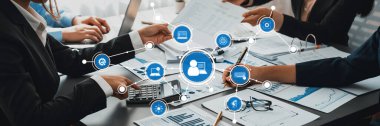Finansal raporlar ve dijital arayüzler etrafında tartışan profesyonellerin yer aldığı dinamik bir iş toplantısı sahnesi, takım çalışmasını ve strateji gelişimini ön plana çıkarıyor. Dostluk