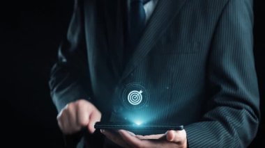 Takım elbiseli bir işadamı dijital pazarlama stratejisi arayüzü gösteren bir akıllı telefon tutuyor, yenilikçi kavramları ve modern iş dünyasının başarısı için analizleri vurguluyor. Dörtgen