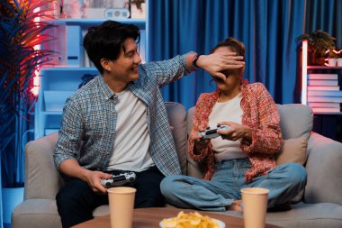 Oyun oynayan mutlu çiftin oturduğu kanepe joystickle oyun oynuyordu. Önden atıştırmalıklar ve kazanmak için gözlerini kapayan içkiler, evdeki modern neon ışıklı oturma odasında eğlenceli bir şekilde meydan okumaydı. İnfobahn.