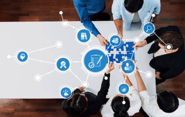 Modern bir çalışma ortamında bulmaca çözen, işbirliğini ve yenilikçi stratejileri sembolize eden çeşitli profesyonellerden oluşan bir grubun tepeden tırnağa görüşü. Dostluk