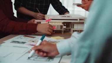 Üyeler mimari modeller ve tasarım planlarıyla etkileşime girerken, proje planlamada yaratıcılığı ve yeniliği teşvik ederken, dinamik toplantı atmosfer gösterme ekibi işbirliği. SACTR