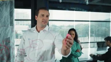 Yetenekli işadamı, cam duvara renkli yapışkan notlar yapıştırarak proje yöneticisine pazarlama fikrini sundu. Proje yöneticisi yatırımcıya projeyi gösteriyor, anlatıyor, gösteriyor. Yönlendirici.