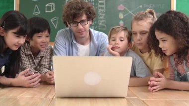 Kafkas öğretmeni ve çeşitli öğrenciler sınıfta dizüstü bilgisayara bakıyor. Kodlama programını öğrenen ya da öğretmenlik yaparken yazılım kullanarak oluşturulan çok kültürlü çocuklar. Pedagoji.