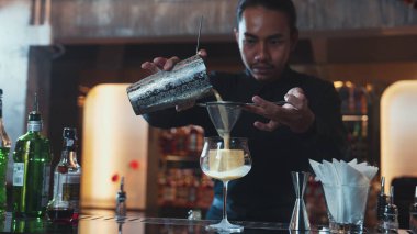 Asyalı barmen, alkollü likör ve şuruplu kokteyl bardağına kattığı her şeyi süzgeçle temizliyor. Lüks gece kulübünde gece hayatı karışımı sergileniyor. Vinosity.