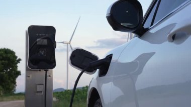 Çevreyi korumak için rüzgar türbininden yeşil ve yenilenebilir enerjiyle çalışan şarj istasyonunda şarj edilen gelişmiş gelecek enerji altyapısı konsepti.