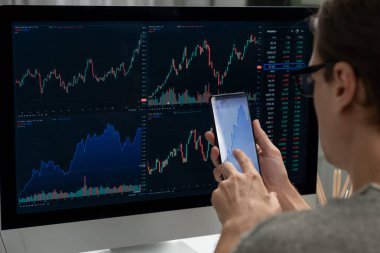Akıllı borsa yatırımcıları ekranda akıllı telefon ile piyasa borsasını işaret ederek dizüstü bilgisayarın yanı sıra en yüksek dinamik yatırım oranını göstererek, modern işyerindeki veri planlamasına odaklanıyorlar. Bireysel.