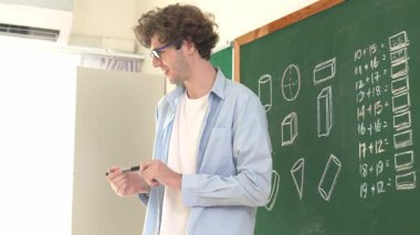 Kafkas öğretmeni tahtada dururken öğrenciye bakıyor. Profesyonel eğitmenin öğrettiği düşük açılı kamera ve çeşitli öğrencilerin sorularına cevap verirken matematik teorisini açıkla. Pedagoji.