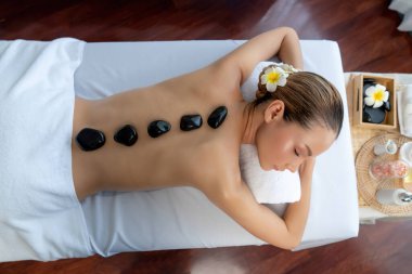 Lüks tatil beldesindeki kaplıca salonunda sıcak taş masajı. Gündüz huzurlu ortam, mutlu kadın müşteri bazalt taşı masajının keyfini çıkarıyor. Sessiz.