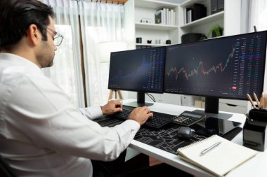 Akıllı tüccar işadamı, modern merkez ofisindeki araştırma pazarında en yüksek kârlı finansal teknolojiye yatırım yaparak bilgisayar üzerinde iki dinamik borsa yatırım ekranını analiz ediyor. Tahmin et..