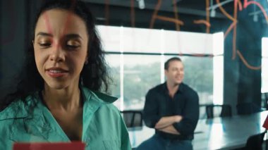 Profesyonel iş adamları yaratıcı pazarlama fikrini modern ofiste tartışırlar. İş adamları cam tahtada yapışkan notlar kullanarak finansal plan üzerinde çalışıyor. Yönlendirici.