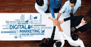 Dijital pazarlama stratejileri üzerinde çalışan çeşitli bir ekibin hava görüşü. Görüntü, çevrimiçi marka varlığını desteklemek için takım çalışmasını ve birliği simgeleyen bir araya gelen elleri gösteriyor. Dostluk