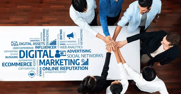 Dijital pazarlama stratejileri üzerinde çalışan çeşitli bir ekibin hava görüşü. Görüntü, çevrimiçi marka varlığını desteklemek için takım çalışmasını ve birliği simgeleyen bir araya gelen elleri gösteriyor. Dostluk