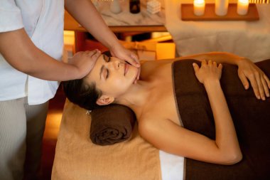 Beyaz kadın stres önleyici kafa masajı yapmaktan ve lüks otel veya otelde sıcak mum ışığında yüz güzelliği eğlencesi yapmaktan zevk alıyor. Sessiz.