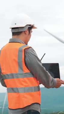 Erkek ve kadın mühendisler kırsal kesimdeki bir tepenin tepesinde ya da dağda rüzgar çiftliğinde çalışıyorlar. Yenilenebilir ve sürdürülebilir enerjinin gelecekteki üretimi için yenilikçi idealler.