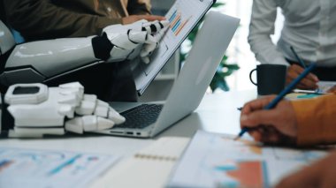 İnsanlar ve robotlar arasındaki işbirliğini gösteren dinamik bir ofis sahnesi, modern işyerlerinde çizelgeler ve dizüstü bilgisayarlarla teknolojinin rolünü vurguluyor.