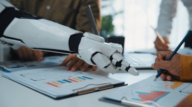 Bir robotik kol, bir iş toplantısı sırasında teknolojinin grafikler ve grafikler hakkındaki tartışmalara entegrasyonunu vurgulayarak yenilik ve takım çalışmasını gösteriyor. Noogenesis