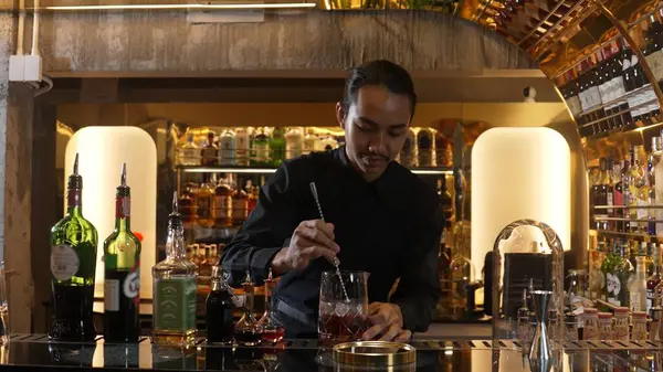 Zeki Asyalı barmen bardakta karıştırılmış alkol şurubunu buzla karıştırıyor. Çünkü kayanın üzerinde kamera var. Gece kulübünde taze kokteyl kokteylleri karıştırıyor. Vinosity.