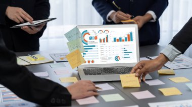 Analizci ekibi yaratıcı ve analitik beyin fırtınası fikri için bilgisayar ekranında BI veri paneli olan yapışkan bir not kullanıyor. Pazarlama stratejisi için finansal veri görselleştirme teknolojisini analiz et. Dahi.