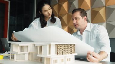 Profesyonel mimar mühendis takım tasarımı ve proje planı kullanarak ev hakkında tartışmalar. Proje yöneticisi, ev inşaatını mimari modeli masaya yerleştirilmiş mühendislere açıklıyor. Yönlendirici.
